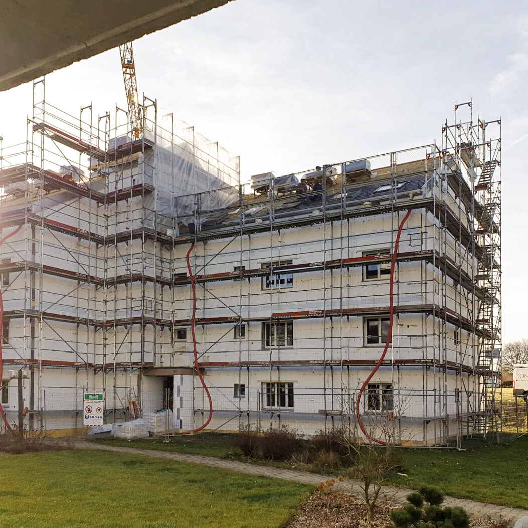 Mehrfamilienhaus mit Baugerüst für Fassadenarbeit der Tony Panitti AG. Firmenfahrzeug der Tony Panitti AG im Hintergrund.