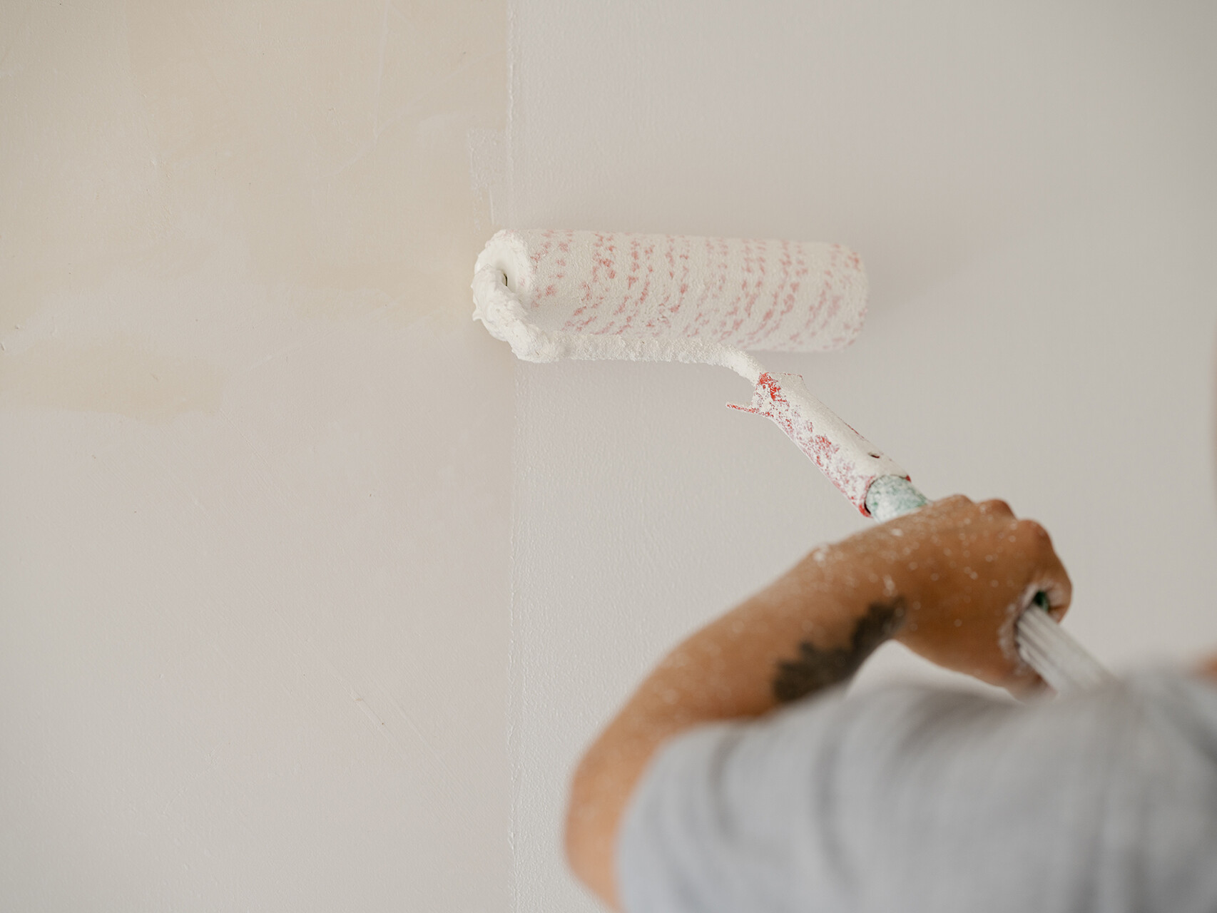 Mitarbeiter macht Voranstrich der Wohnzimmerwand einer Wohnung in Köniz bei Bern.